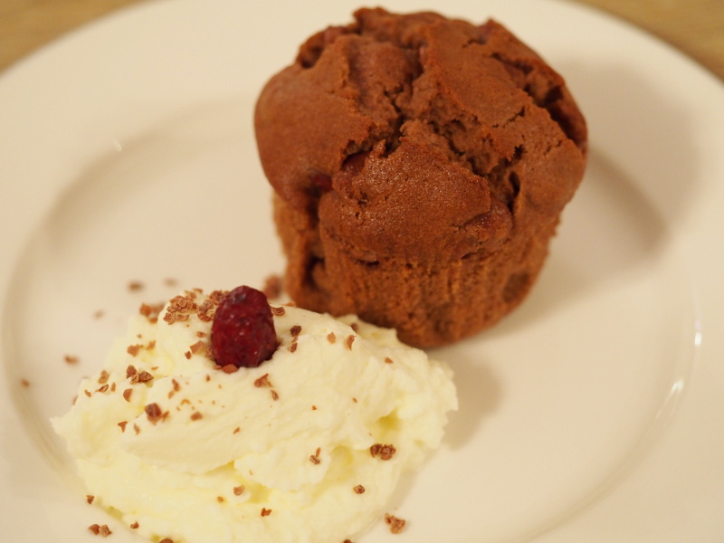 Ein Schokoladenmuffin auf einem Teller mit einem Klecks Sahne davor.