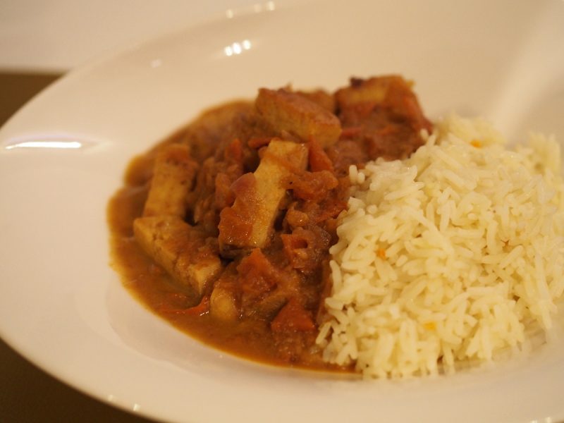 Eine Portion des Curry auf einem Teller mit Reis.