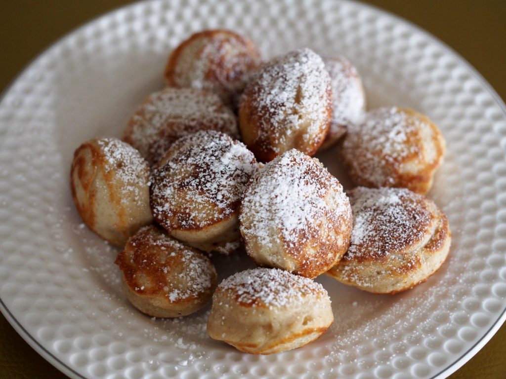 Einige Poffertjes mit Puderzucker bestäubt auf einem Teller
