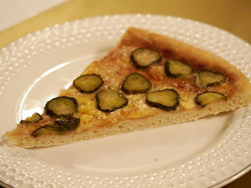 Eine Pizza belegt mit saure Gurkenscheiben.