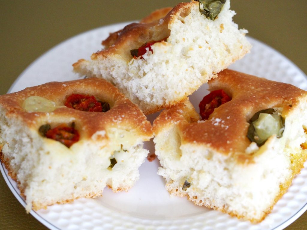 Drei Stücke Focaccia mit Tomaten und Basilikum in den einzelnen Vertiefungen des italienischen Brots