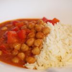 Eine Portion des Kichererbsen Curry mit Reis auf einem Teller.