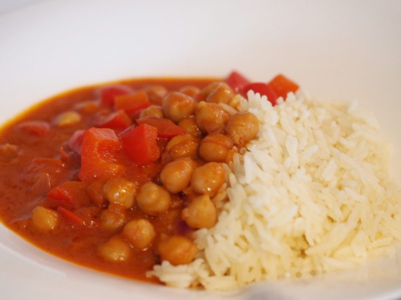 Eine Portion des Kichererbsen Curry mit Reis auf einem Teller.