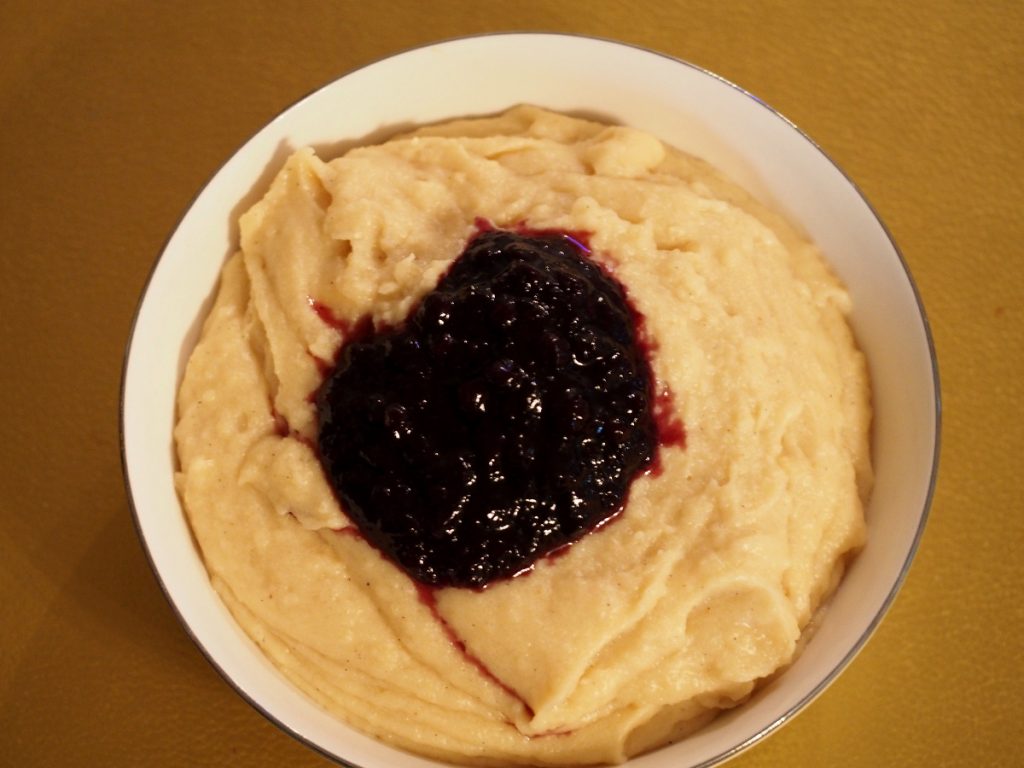 Eine Schüssel Grießbrei mit etwas Blaubeermus in der Mitte.