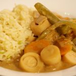 Eine Portion des Curry mit Palmherzen neben etwas Reis.