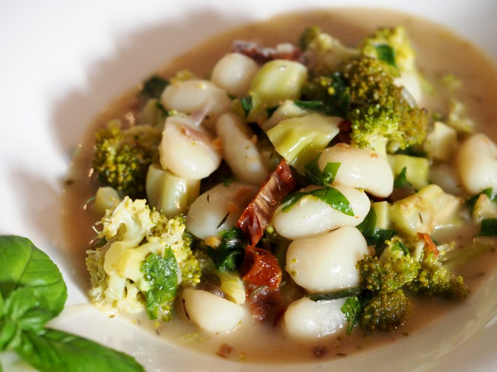 Gnocchi mit Brokkoli, getrockneten Tomaten und frischem Basilikum auf einem Teller