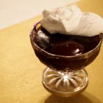 Eine Dessertschüssel mit etwas Rotwein-Pflaumen-Pudding und etwas Sahne darauf