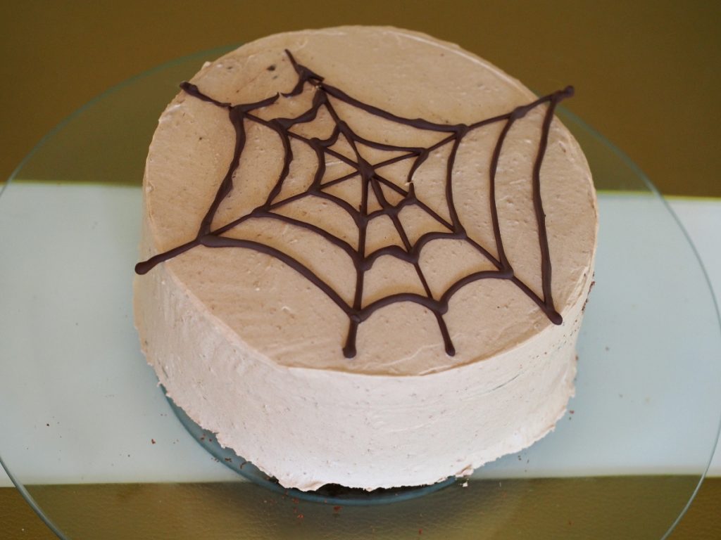 Die noch ganze Torte mit einem Spinnennetz aus Schokolade