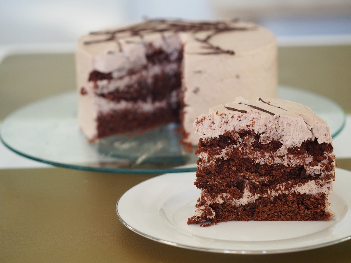 Die angeschnittene Schokoladen-Minz Torte im Hintergrund, davor ein einzelnes Stück auf einem Teller