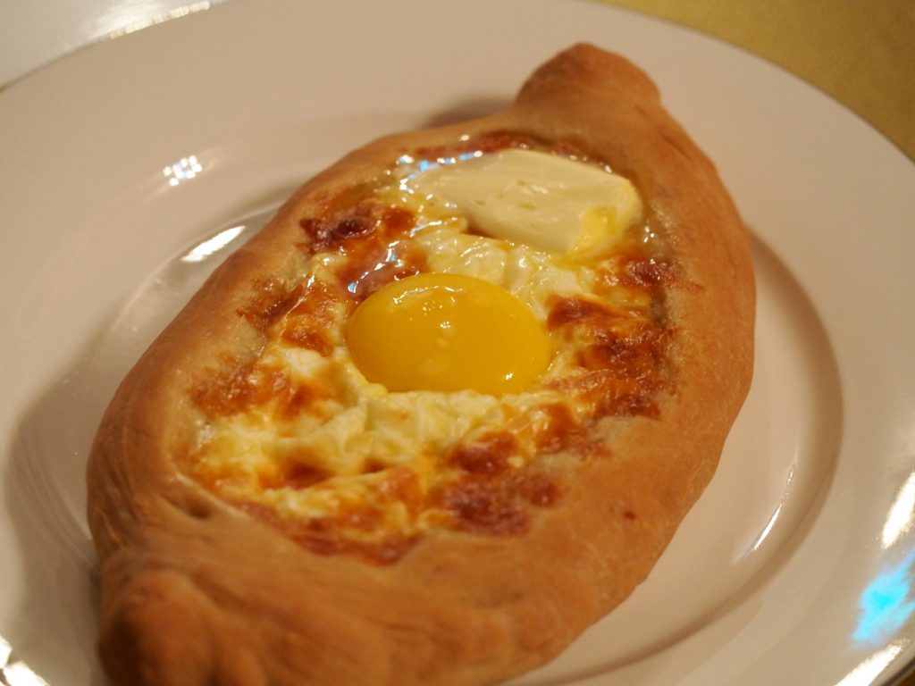 Das fertige georgische Käseboot mit einem Ei in der Mitte und ein Stückchen Butter