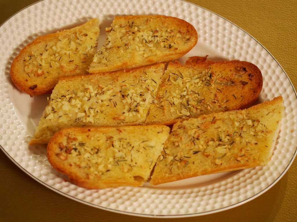 Ein paar Stücke eines Knoblauchbaguettes auf einem Servierteller