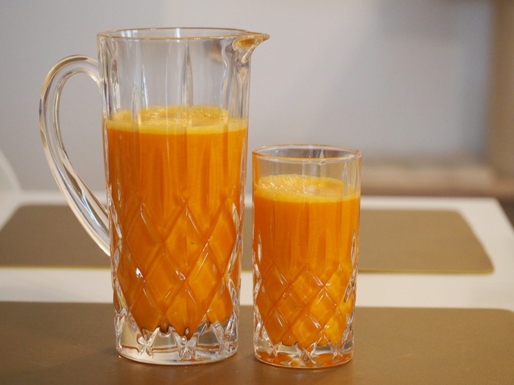 Ein Glas und eine Karaffe gefüllt mit Kürbissaft