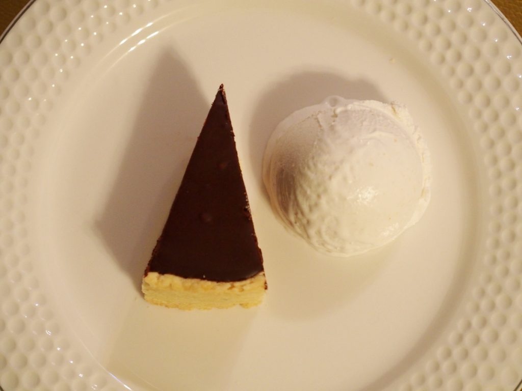 ein kleines Stück einer Schokoladentarte neben einer Kugel Ingwereiscreme