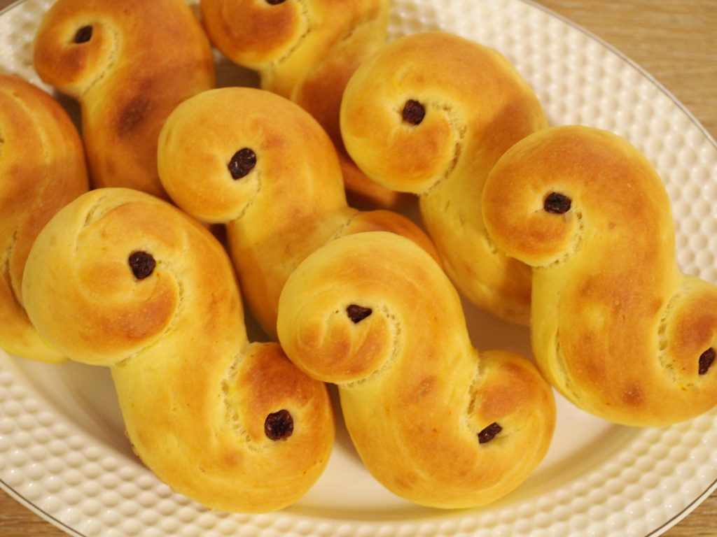 Einige goldgelb gebackene Lussekatter auf einem Servierteller