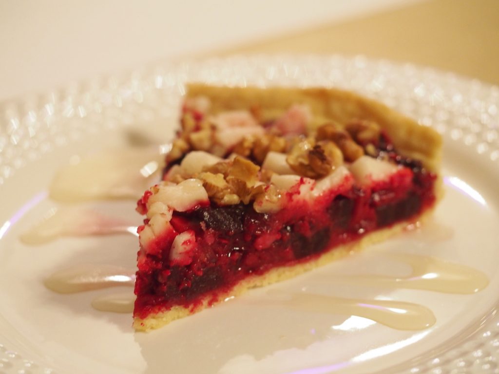 Ein Stück einer rote Bete Quiche mit veganem Hirtenkäse und Walsnüssen
