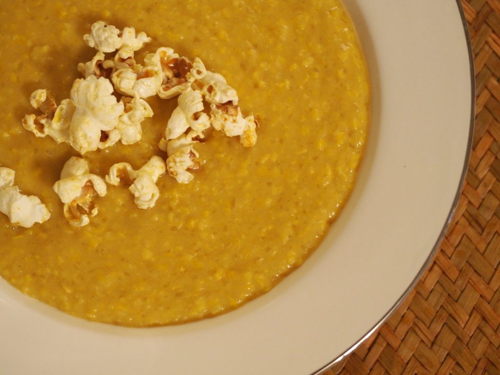 Maissuppe in einem Teller, getoppt mit etwas pikanten Popcorn