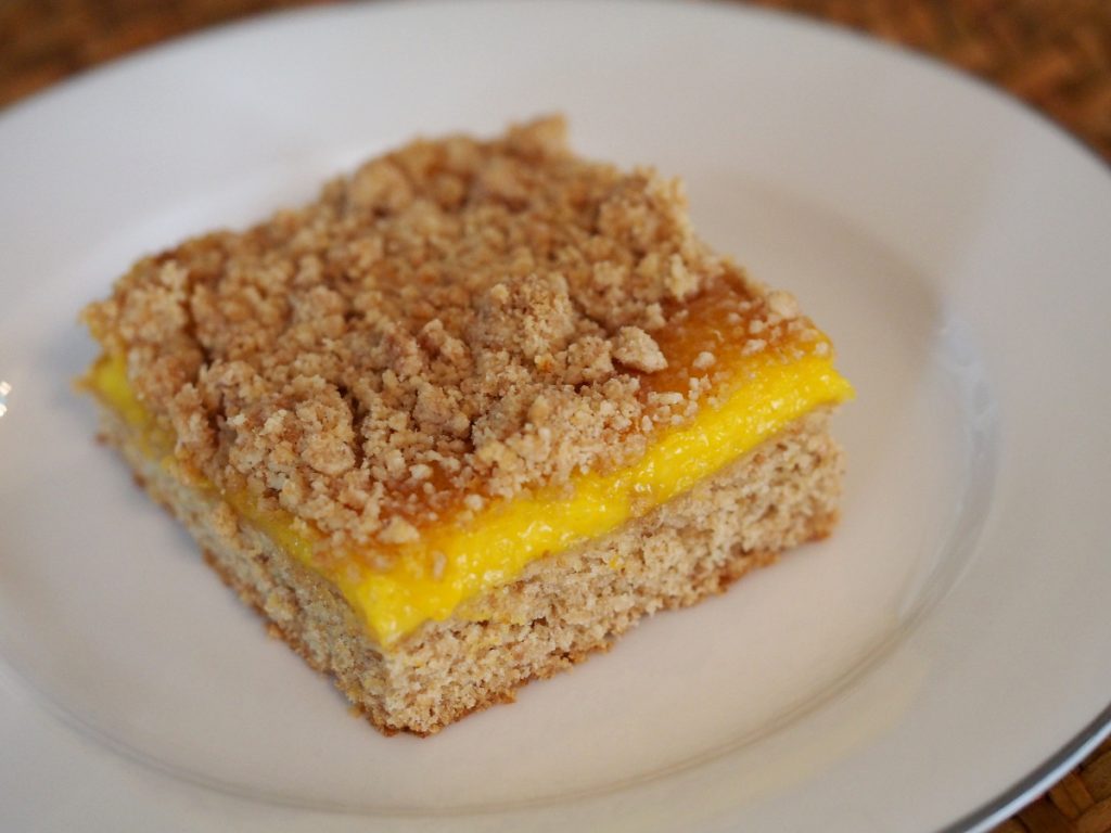 Ein Stück Streuselkuchen mit Mandarinenfüllung auf einem Kuchenteller