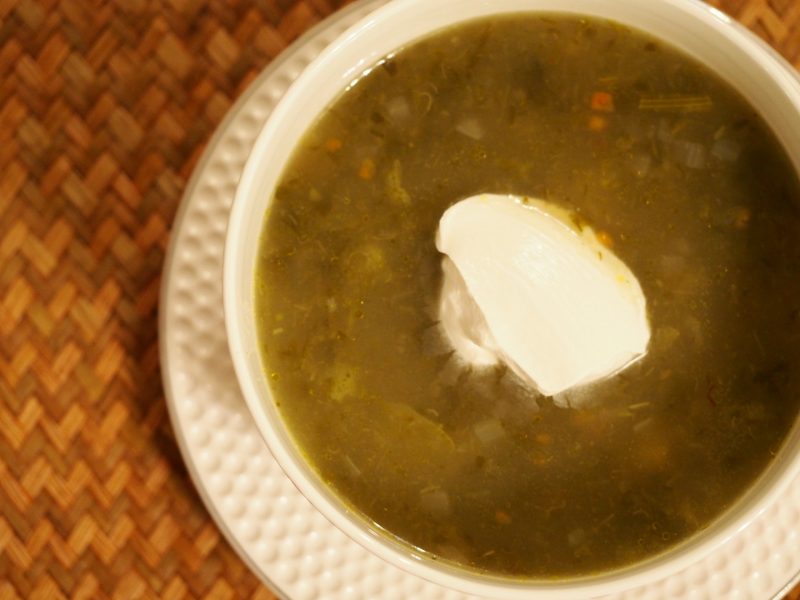 Eine Portion Sauerampfer Suppe mit Karoffeln und mit einem Klecks veganer sauren Sahne als Dekoration in der Mitte
