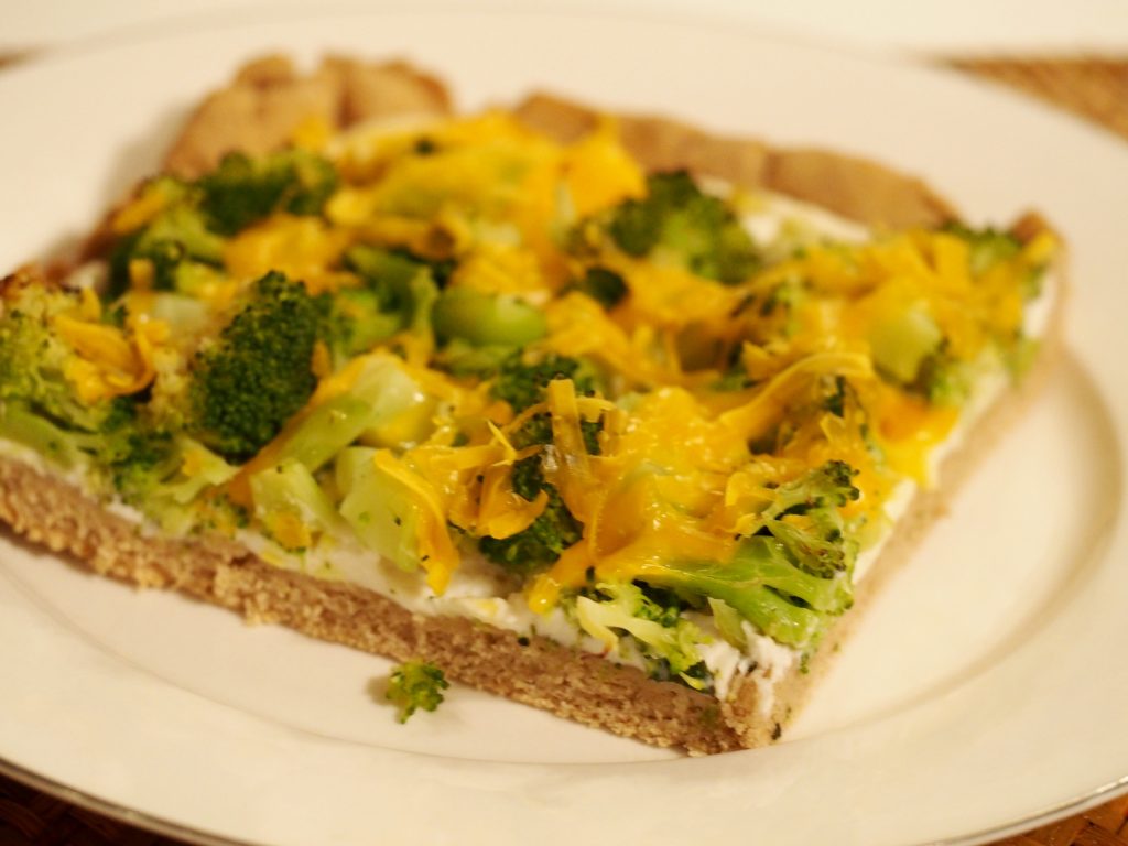 Ein Stück der Brokkolipizza mit veganem Käse überbacken