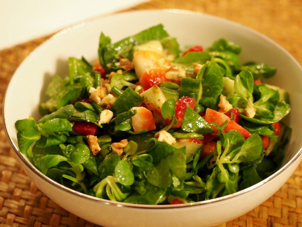 Grüner Salat mit frischen Erdbeeren in einer weißen Schüssel