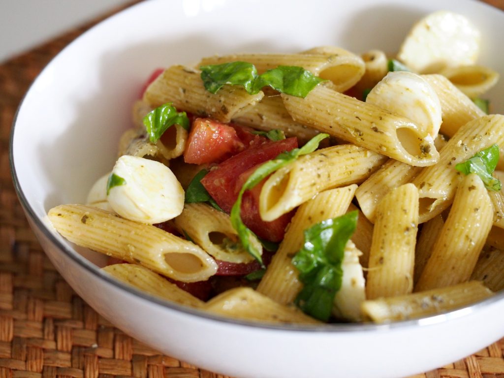 Ein italienischer Nudelsalat mit Pesto, Tomaten, Mozzarella und Basilikum