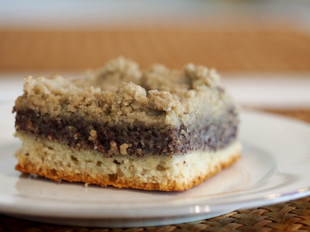 Ein Stück des Mohnkuchen mit einer dicken Schicht der Mohnfüllung in der Mitte mit Streuseln darauf