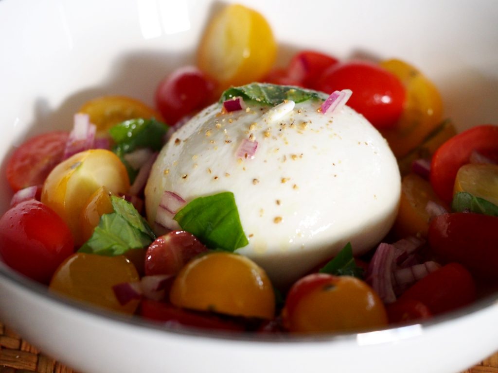 Burrata in mitten eines frischen Tomatensalats in einer Schüssel