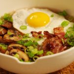 Ein asiatisches Congee mit Ei, gebratenem Speck und gebratenen Champignons