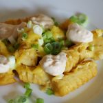 Überbackene Kartoffelkroketten, dekoriert mit Frühlingszwiebel