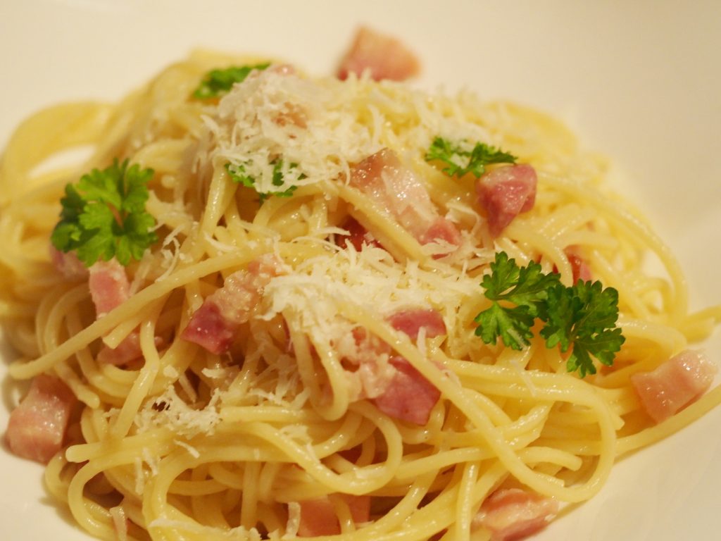 Eine Portion der Pasta alla gricia auf einem Teller, dekoriert mit etwas frischer Petersilie