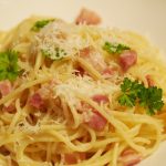 Eine Portion der Pasta alla gricia auf einem Teller, dekoriert mit etwas frischer Petersilie