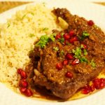Eine geschmorte Entenkeule mit einer Granatapfelsauce neben Reis.