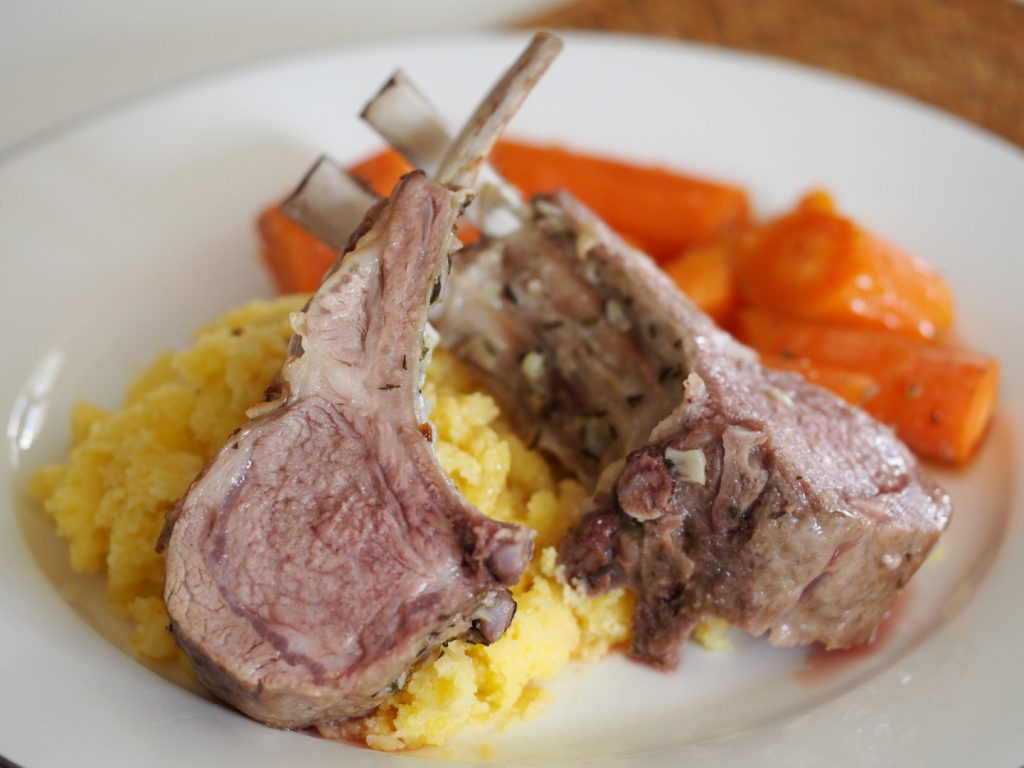 Zwei Stücke des Lammkarree auf Polenta mit Karottengemüse daneben