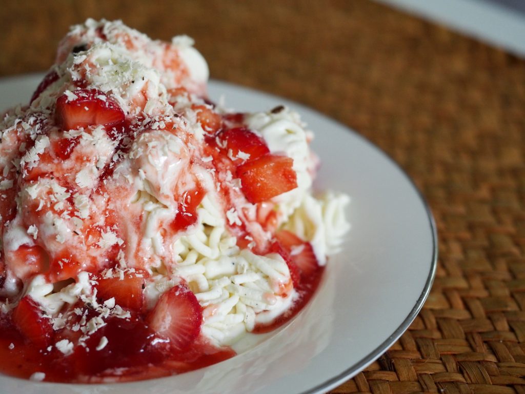 Eine Portion Spaghettieis mit Erdbeersauce und frischen Erdbeeren.