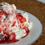 Eine Portion Spaghettieis mit Erdbeersauce und frischen Erdbeeren.
