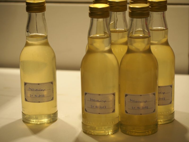 Einige Flaschen mit dem abgefüllten Zitronenmelissensirup stehen auf der Arbeitsfläche