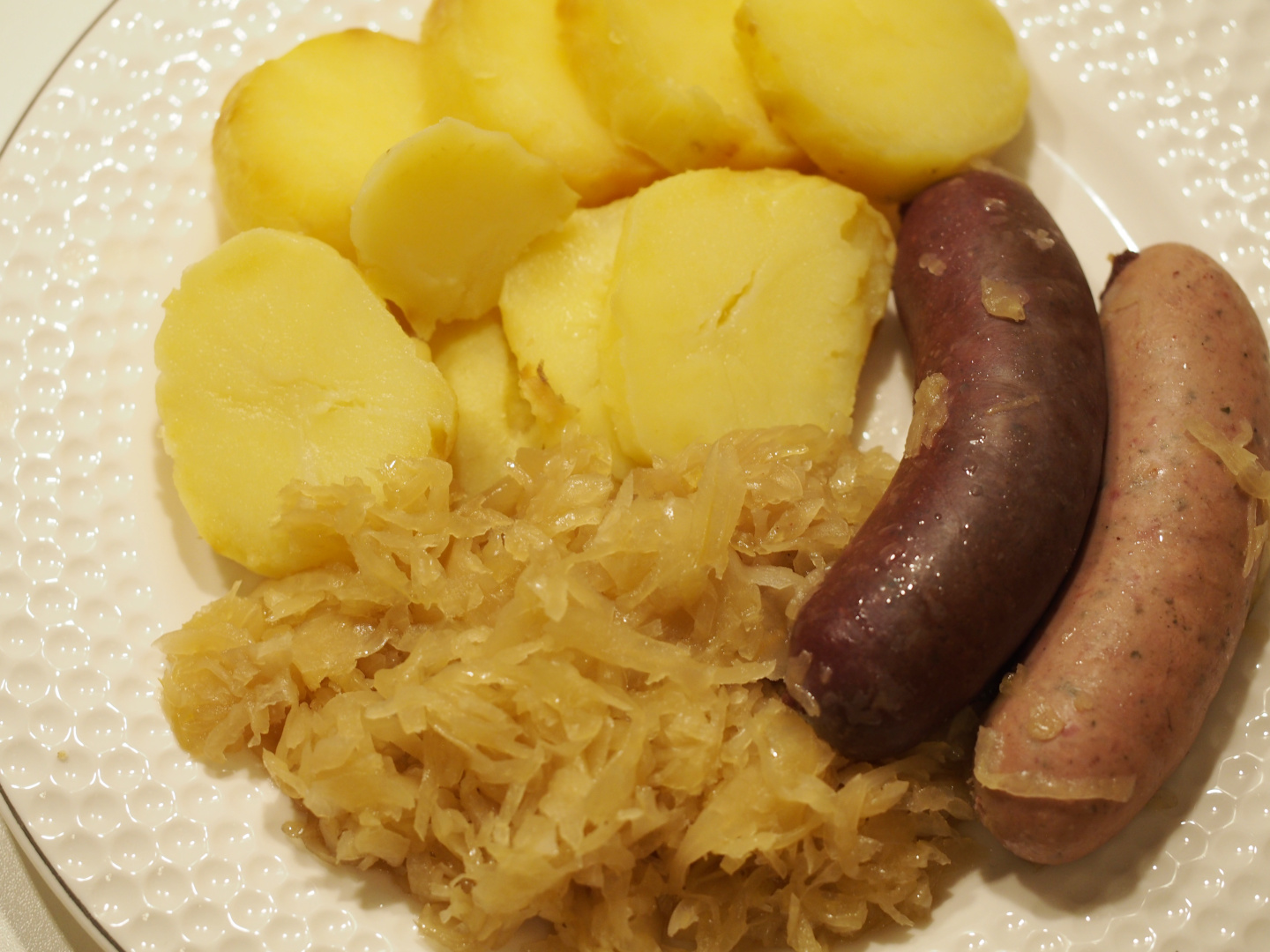 Gekochte Blut- und Leberwurst auf Sauerkraut neben ein paar Kartoffelscheiben