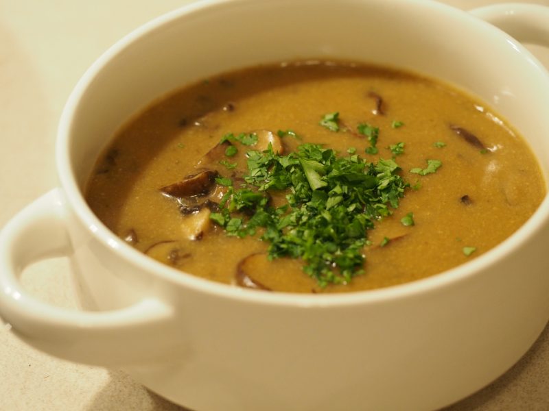 Eine Suppentasse gefüllt mit der Champignon Suppe, dekoriert mit etwas gehackter Petersilie