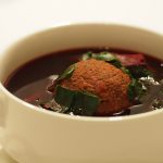Eine klare rote Bete Suppe mit einem großen Leberknödel in einer Suppentasse