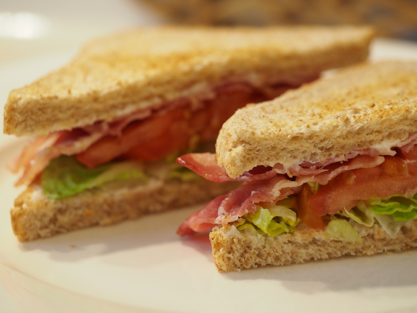 Ein diagonal aufgeschnittenes Sandwich mit Bacon, Salat und Tomate