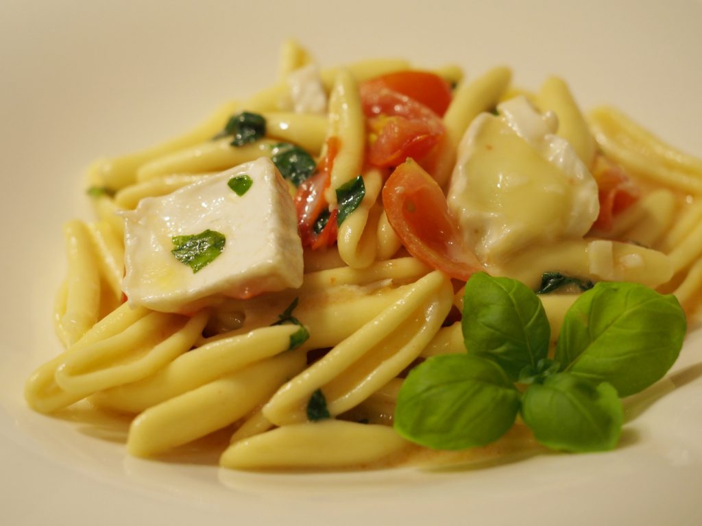 Eine Portion der Brie Cheese Pasta auf einem Teller, dekoriert mit ein paar frischen Blättern Basilikum