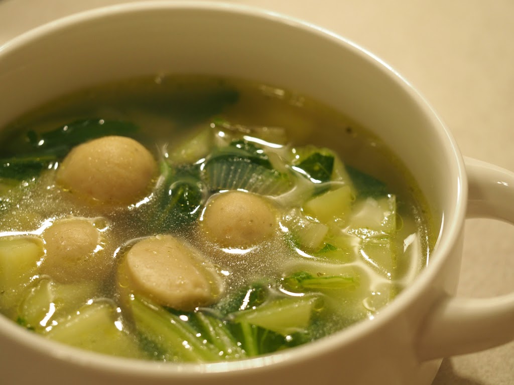Eine Suppentasse gefüllt mit der klaren Kartoffelsuppe mit Markklößchen und Pak Choi