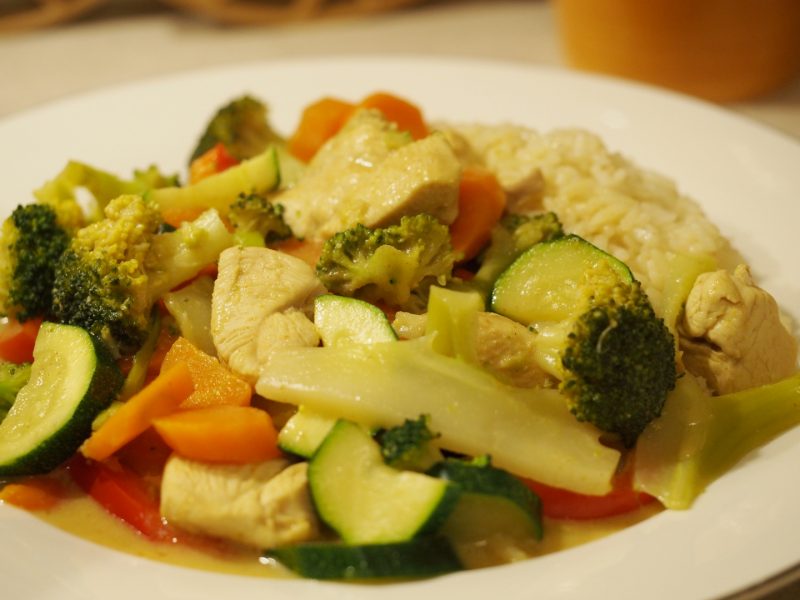 Ein Teller mit dem Thaicurry mit buntem Gemüse und Reis.