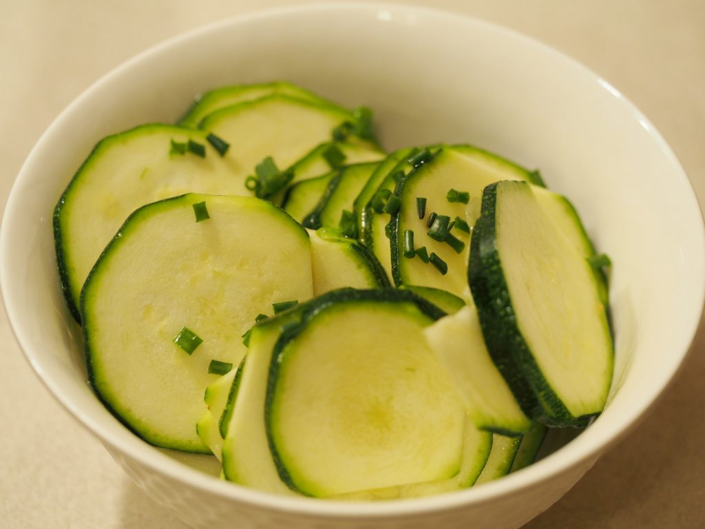 Eine Portion des Zucchinisalat in einer kleinen Schüssel, garniert mit etwas Schnittlauch