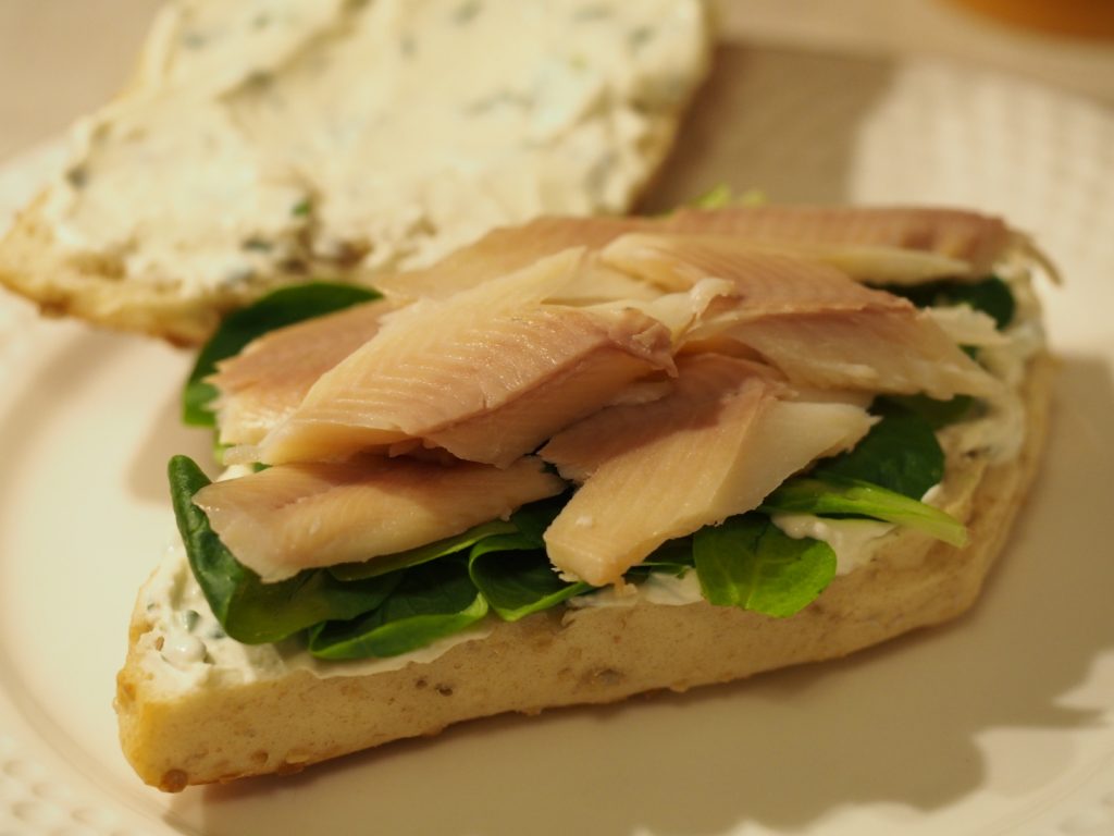 Das zubereitete Sandwich mit einem Belag aus geräucherter Forelle, Feldsalat und einem Frischkäse-Meerrettich Aufstrich mit Schnittlauch