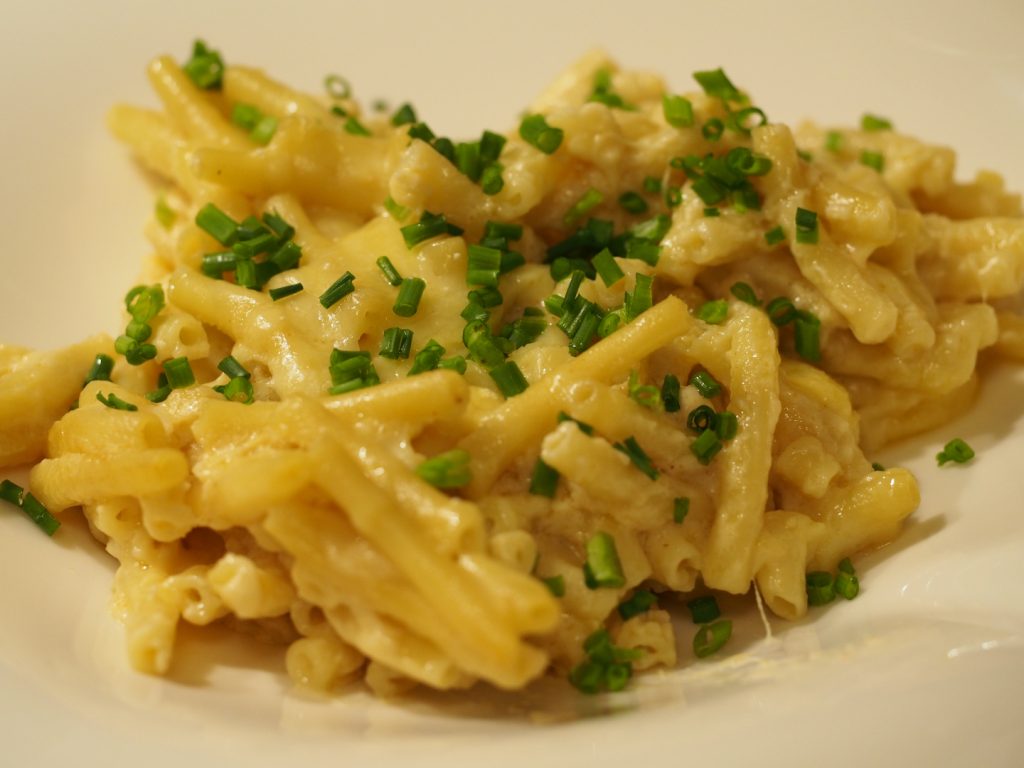 Eine Portion des Mac and Cheese garniert mit geschnittenem Schnittlauch auf einem Teller