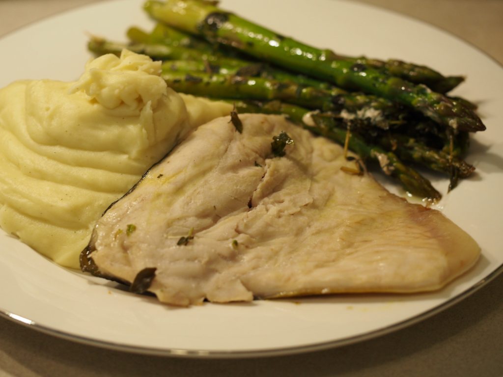 Ein im Backofen gegartes Karpfenfilet mit grünem Spargel und Kartoffelbrei
