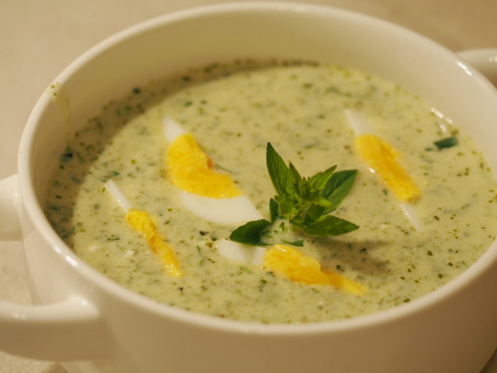Eine Suppentasse gefüllt mit einer Oregano Suppe mit gevierteltem hart gekochtem Ei
