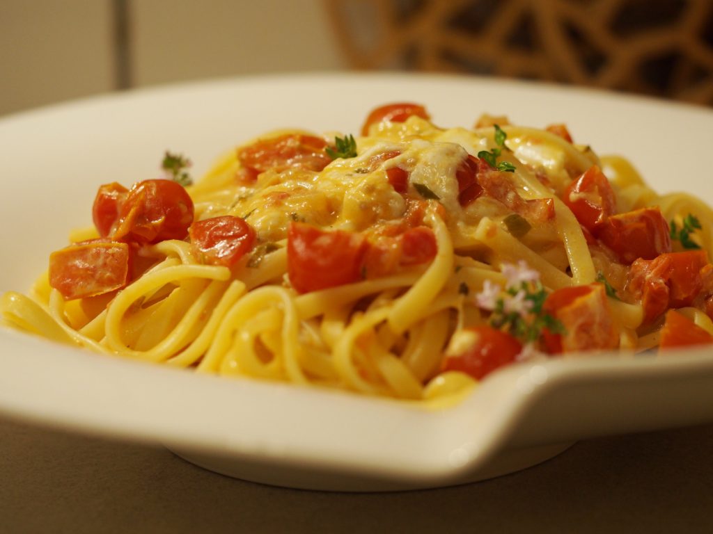 Eine Portion Pasta mit einer Tomaten-Burrata Sauce auf einem Pastateller.