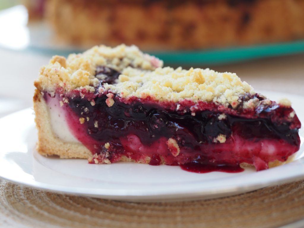 Ein Stück des Streuselkuchen mit Apfelbeerenfüllung und Cremeschicht unten drunter.